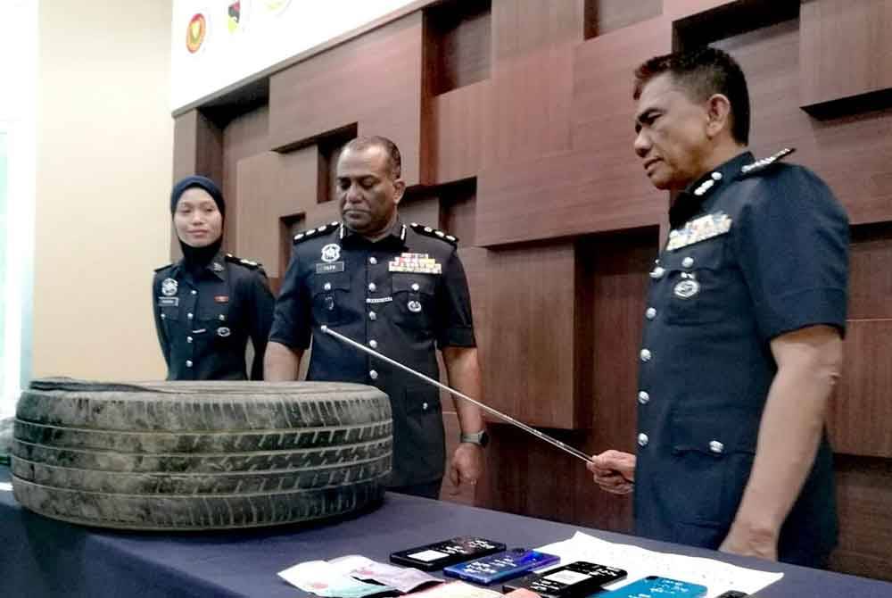 Fisol (kanan) menunjukkan tayar ganti yang ditoreh untuk memasukkan dadah jenis syabu yang diletakkan di bahagian bawah kenderaan terbabit.