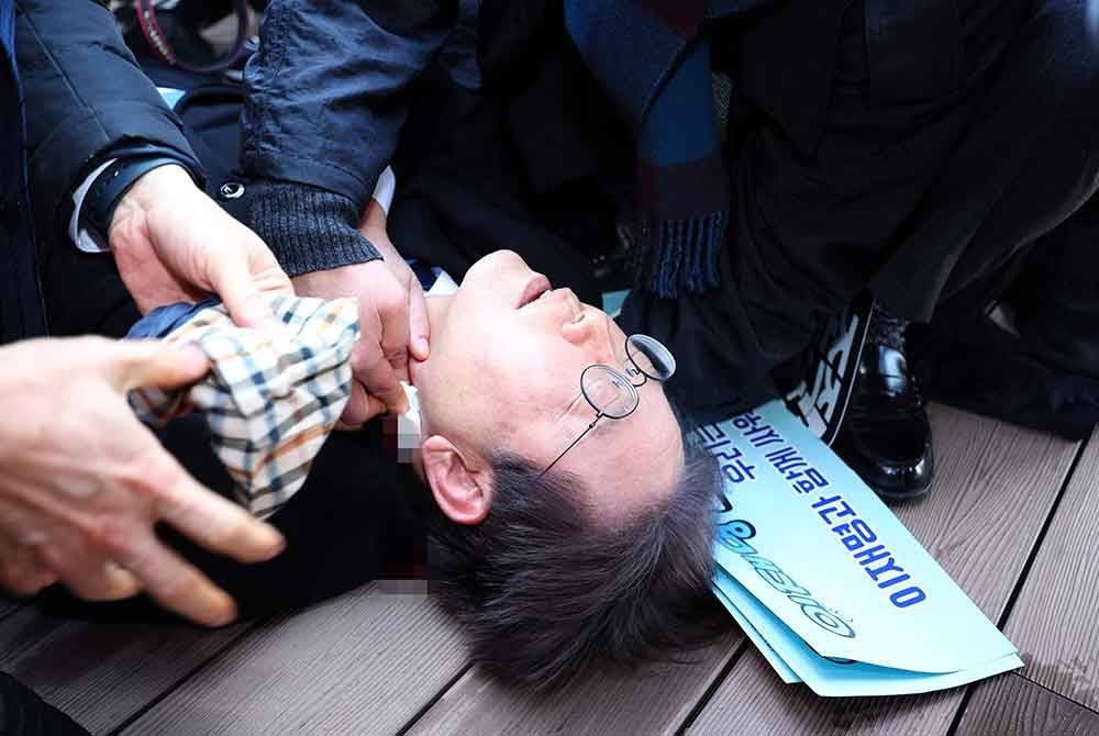 Lee Jae Myung diserang di bahagian kiri leher oleh seorang lelaki tidak dikenali ketika sesi soal jawab selepas meninjau tapak pembinaan lapangan terbang baharu di Pulau Gadeok, Busan. Foto AFP