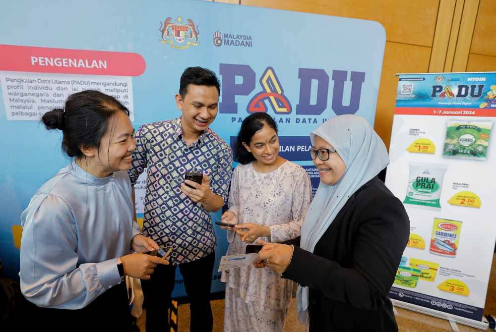 Kakitangan Jabatan Perangkawan, Khairunnisa Khaidir (kanan) membantu orang ramai mendaftar dan mengakses PADU yang dilancarkan hari ini. Foto Bernama