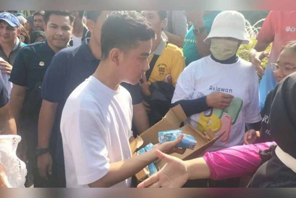 Gibran ketika mengagihkan susu percuma ketika hari bebas kenderaan di Jakarta pada bulan lalu. Foto Agensi