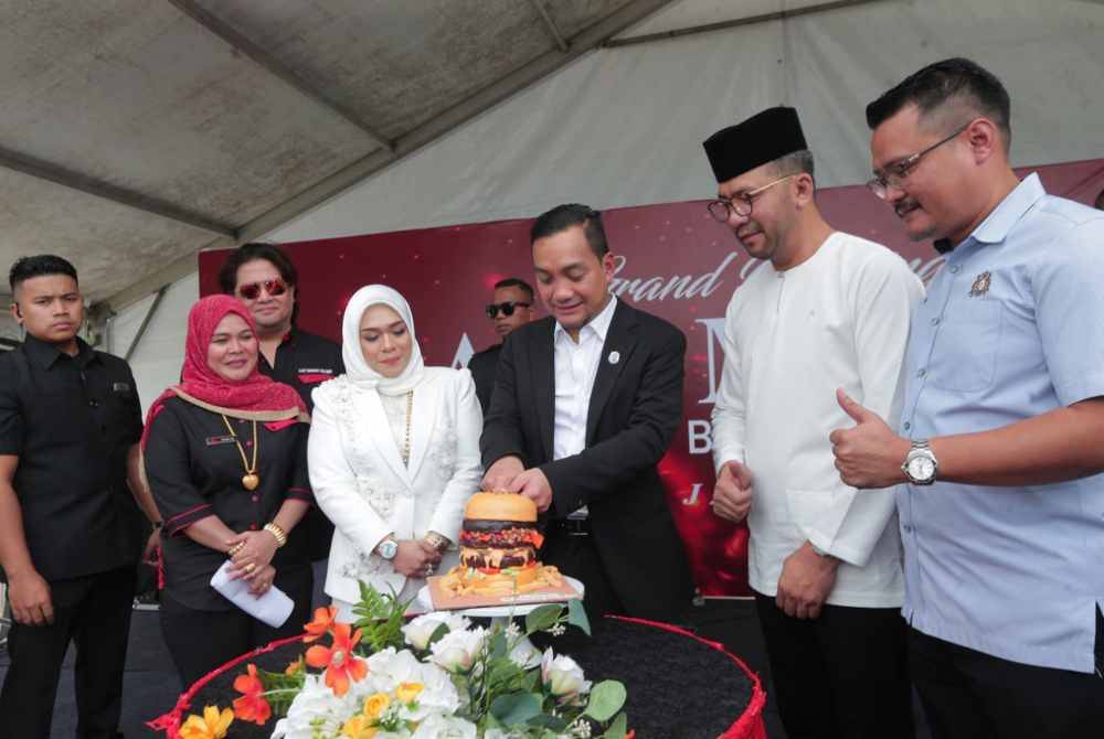 Mohd Hairi (kanan) melihat Onn Hafiz memotong burger sebagai simbolik perasmian Outlet Lazy Monday di Tebing@Bandar Dato Onn, Johor Bahru, pada Rabu.