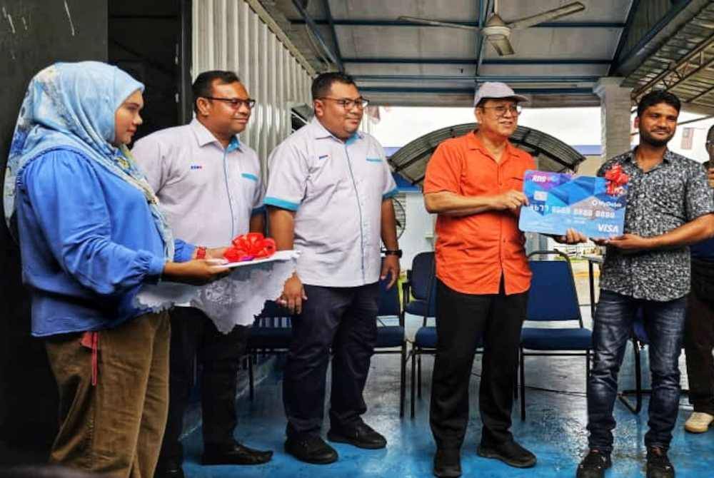 Zamri (dua dari kanan) menyerahkan replika kad kepada seorang pekerja ladang tersebut sempena perasmian perkhidmatan tersebut di ladang terbabit.