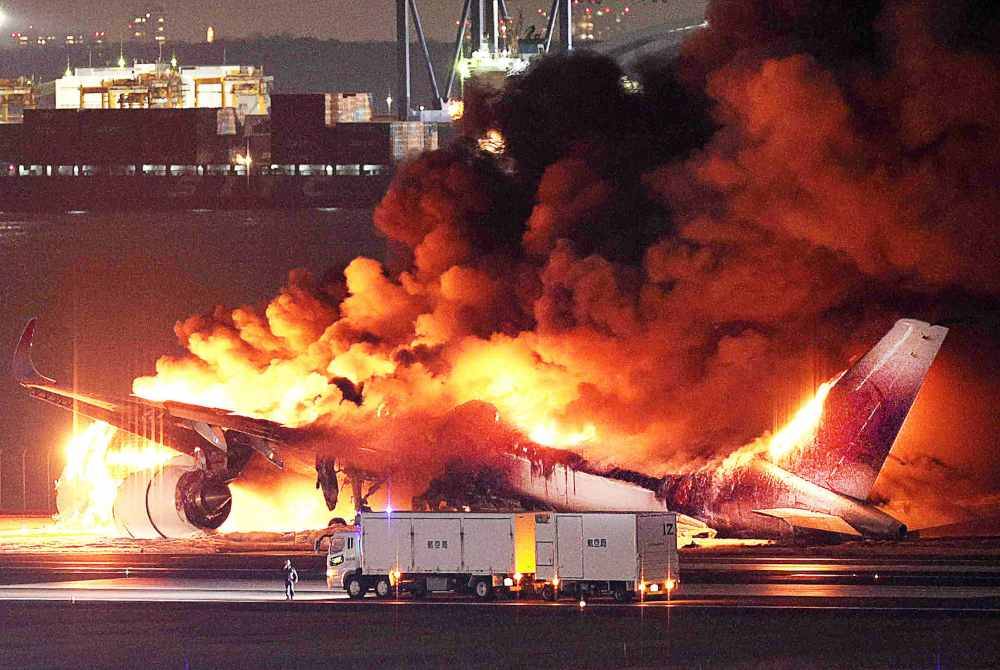 Pesawat Japan Airlines terbakar di landasan Lapangan Terbang Haneda, Tokyo pada Selasa selepas berlanggar dengan sebuah pesawat pengawal pantai. Foto Jiji Press/ AFP