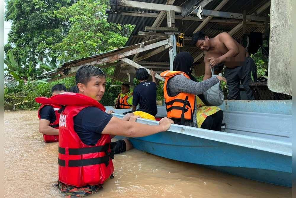 Anggota bomba membantu penduduk Kampung Sentosa Damai, Johor Bahru, pada Khamis berpindah selepas kediaman mereka banjir. Foto ihsan Bomba Johor