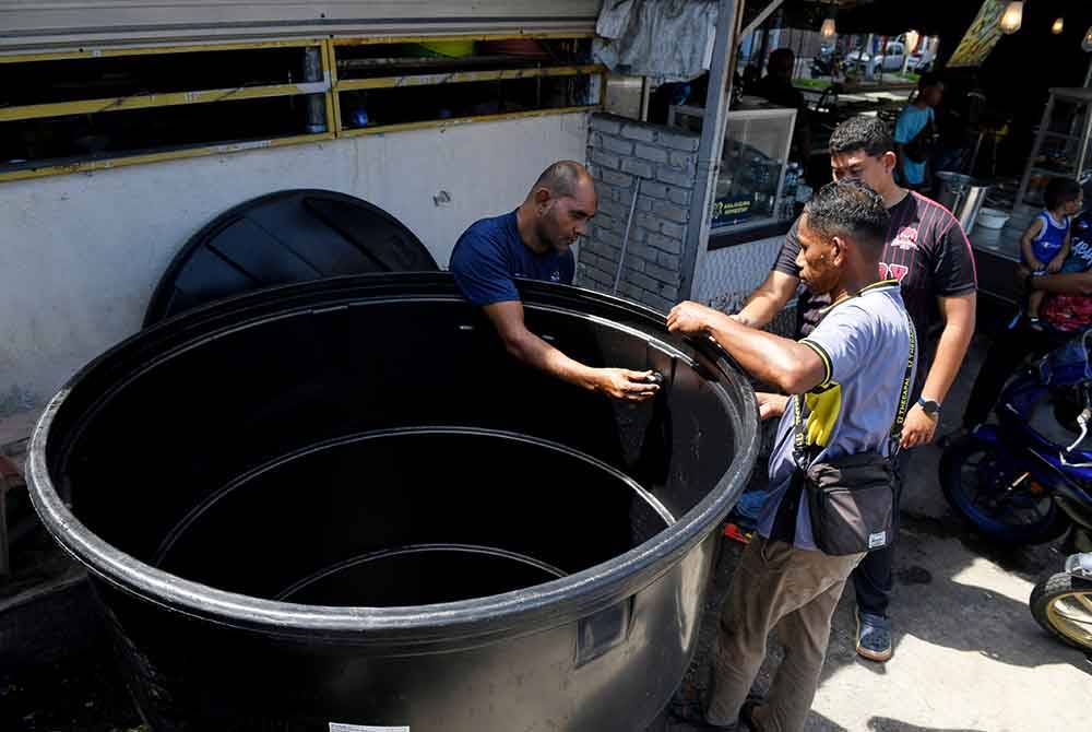 Pekerja membuat kerja-kerja pemasangan paip pada tong air besar untuk menyimpan air sebagai persiapan menghadapi gangguan bekalan air yang dijangka berlaku pada minggu depan. - Foto Bernama