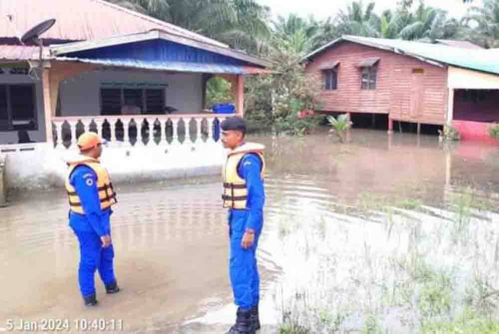 Anggota Angkatan Pertahanan Awam Malaysia (APM) Kluang meninjau keadaan banjir di Kampung Contoh Kahang, Kluang pada Jumaat. Foto ihsan APM