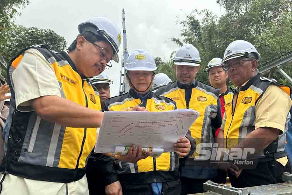 Nanta (dua dari kiri) mendengar penerangan berkaitan perkembangan kerja pemasangan jambatan panel keluli bermodular di Jeli pada Sabtu.