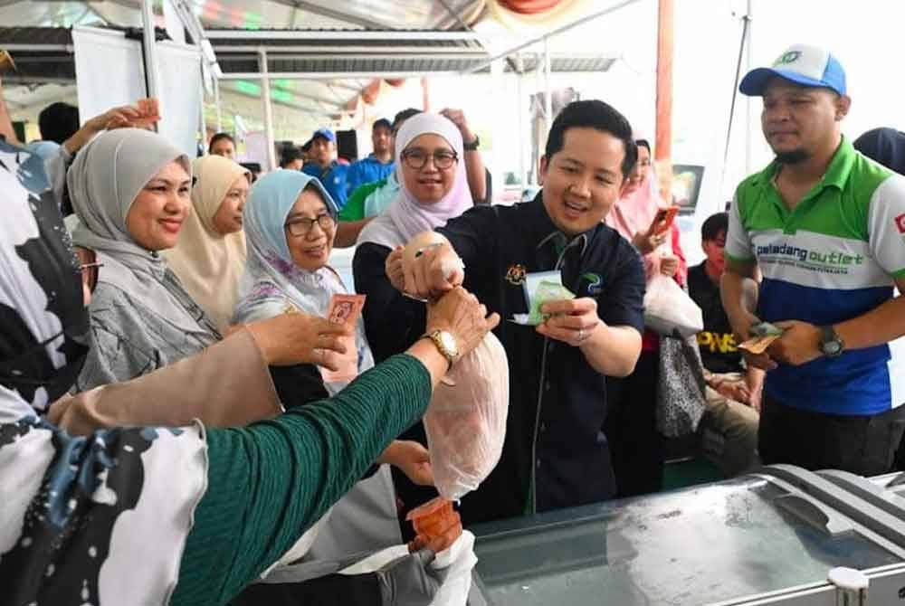 Arthur bersama pengunjung yang membeli ayam dengan harga runtuh RM7 sekilogram. FOTO KPKM