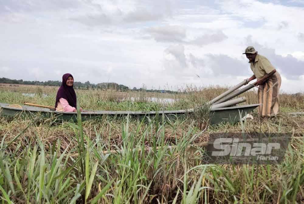 Mail (kanan) memasukkan tukir ke dalam perahu untuk diletakkan di kawasan yang dikesan ada belut.