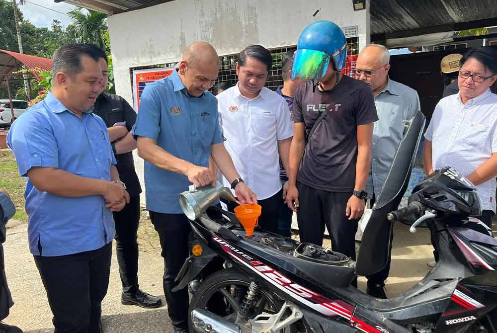 Armizan mengisi petrol sebuah motosikal ketika lawatan kerjanya dalam Program Community Drumming di Tenom.