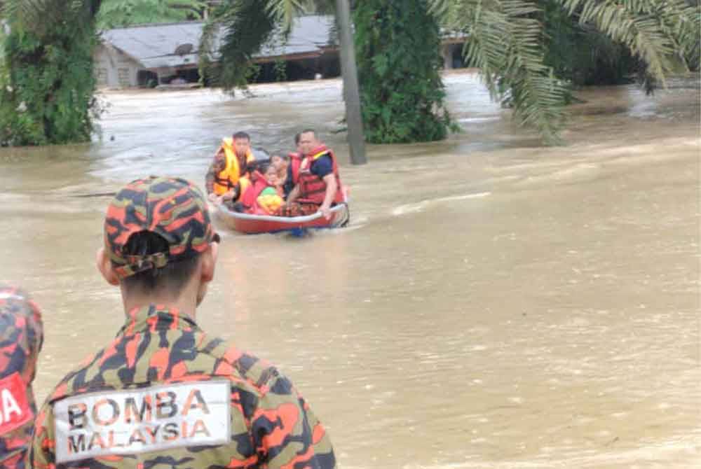 Anggota bomba membantu memindahkan penduduk terjejas akibat banjir di sekitar Johor Bahru. Foto Bomba