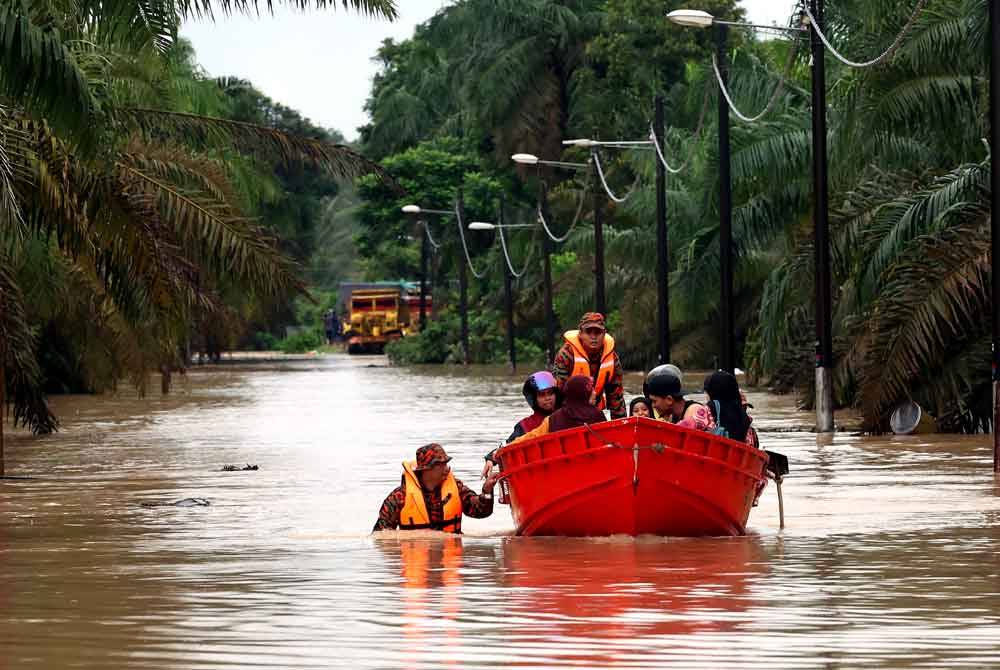 Anggota Jabatan Bomba dan Penyelamat Malaysia (JBPM) membantu memindahkan penduduk Kampung Batu 20 dan Kampung Bukit Dagang, Sungai Tiram yang terputus hubungan selepas jalan utama memasuki perkampungan itu dinaiki air akibat limpahan air sungai berdekatan pada Ahad. Foto Bernama