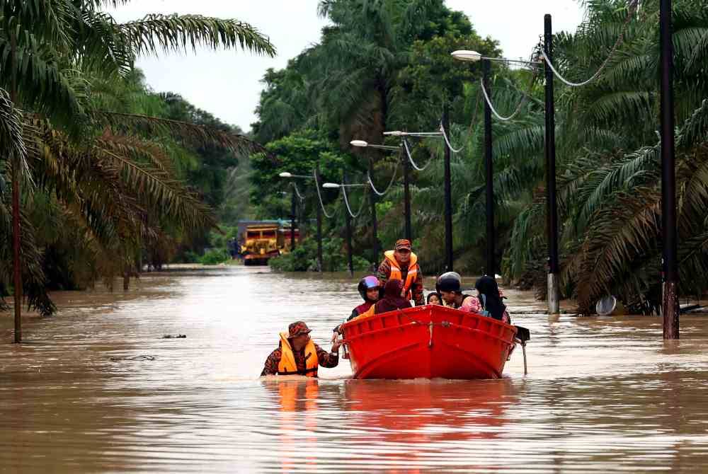 Anggota Jabatan Bomba dan Penyelamat Malaysia (JBPM) membantu memindahkan penduduk Kampung Batu 20 dan Kampung Bukit Dagang, Sungai Tiram yang terputus hubungan selepas jalan utama memasuki perkampungan itu dinaiki air. Foto Bernama