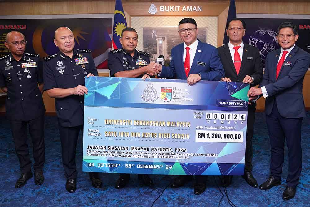 Ayob Khan (tiga, kiri), menyerahkan replika cek kepada Naib Canselor, UKM, Profesor Datuk Dr Mohd Ekhwan Toriman (tiga, kanan), ketika Mesyuarat Jawatankuasa Pemandu Pelaksanaan Usahasama PDRM bersama Universiti Kebangsaan Malaysia (UKM) di Bukit Aman, di sini, pada Isnin. Foto Sinar Harian MOHD HALIM