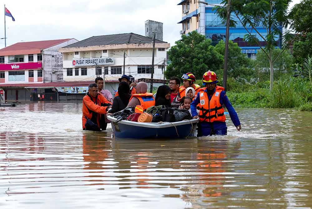 Anggota Angkatan Pertahanan Awam Kota Tinggi membantu menyelamatkan mangsa banjir yang terperangkap di sekitar Pusat Bandar Kota Tinggi ketika tinjauan hari ini. Foto Bernama