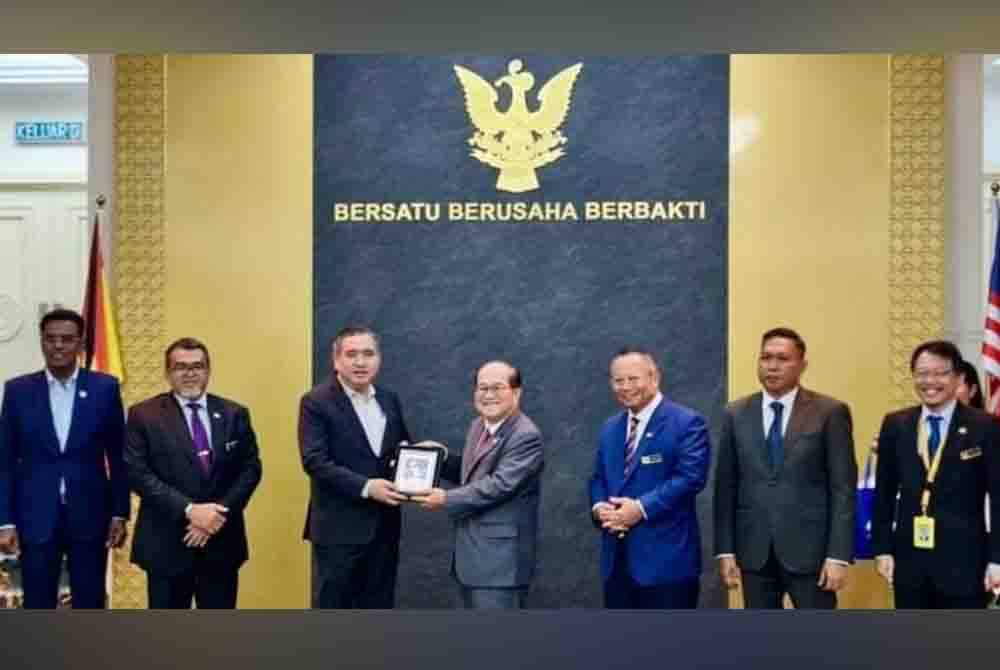 Uggah menyampaikan cenderahati kepada Anthony Loke selepas mesyuarat Jawatankuasa Bersama Persekutuan - Negeri di Kuching pada Isnin.