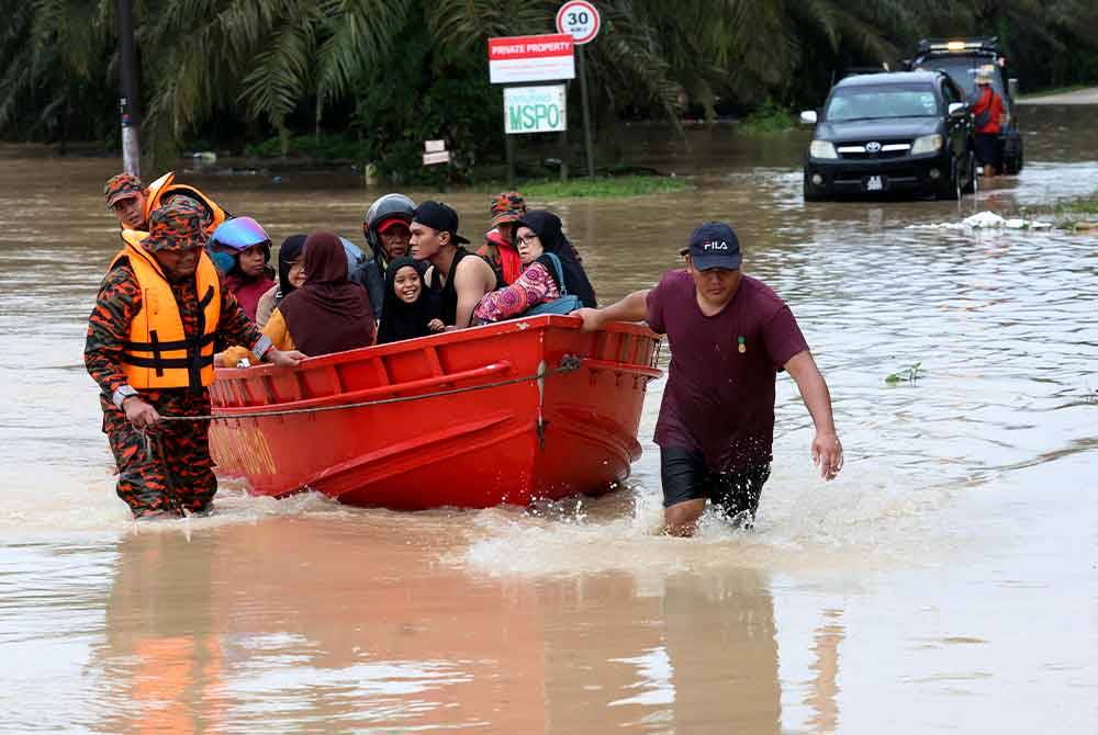 Anggota Jabatan Bomba dan Penyelamat Malaysia (JBPM) membantu memindahkan penduduk Kampung Batu 20 dan Kampung Bukit Dagang, Sungai Tiram, Johor Bahru yang terputus hubungan selepas jalan utama memasuki perkampungan itu dinaiki air akibat limpahan air sungai berdekatan pada Ahad. Foto Bernama