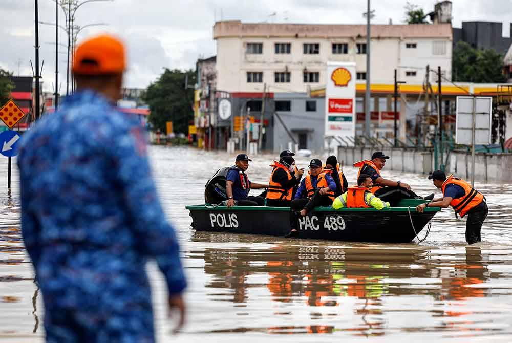 Anggota polis menggunakan bot penyelamat bagi membawa mangsa-mangsa yang terperangkap akibat bencana banjir di Pusat Bandar Kota Tinggi pada Selasa. Foto Bernama