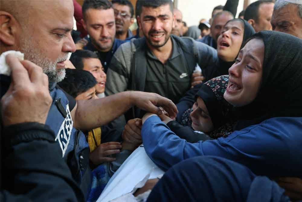 Balu Hamza Wael Dahdouh (kanan) meratapi jenazah suaminya semasa pengebumian wartawan Al Jazeera itu, selepas dia terbunuh ketika melaporkan serangan udara Israel di Rafah di Semenanjung Gaza pada 7 Januari 2024. Foto AFP