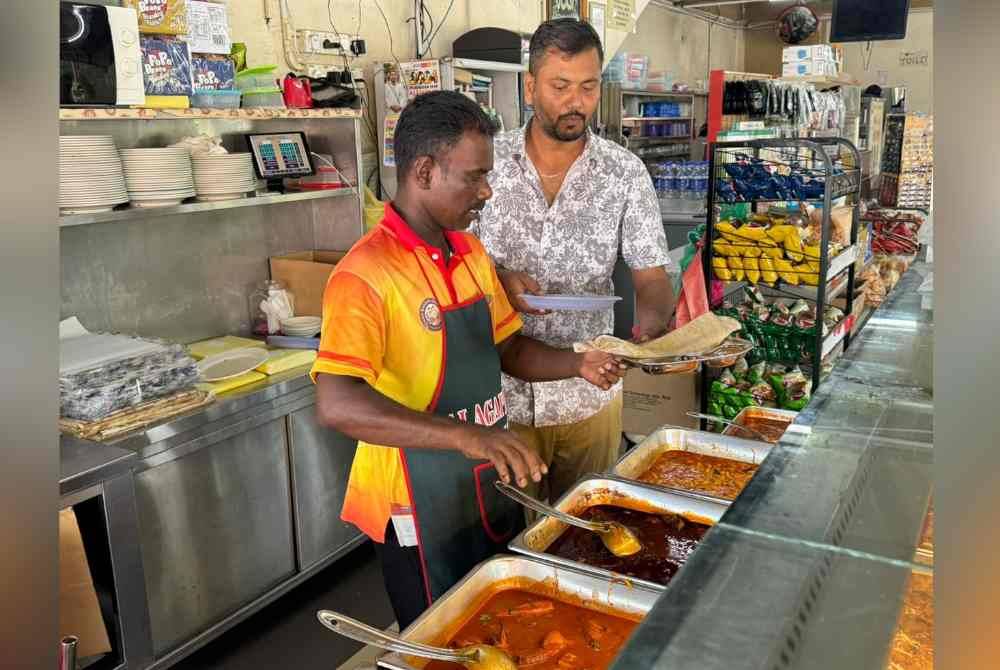 
Abbas (kanan) membantu salah seorang pekerjanya menyediakan makanan kepada pelanggan.