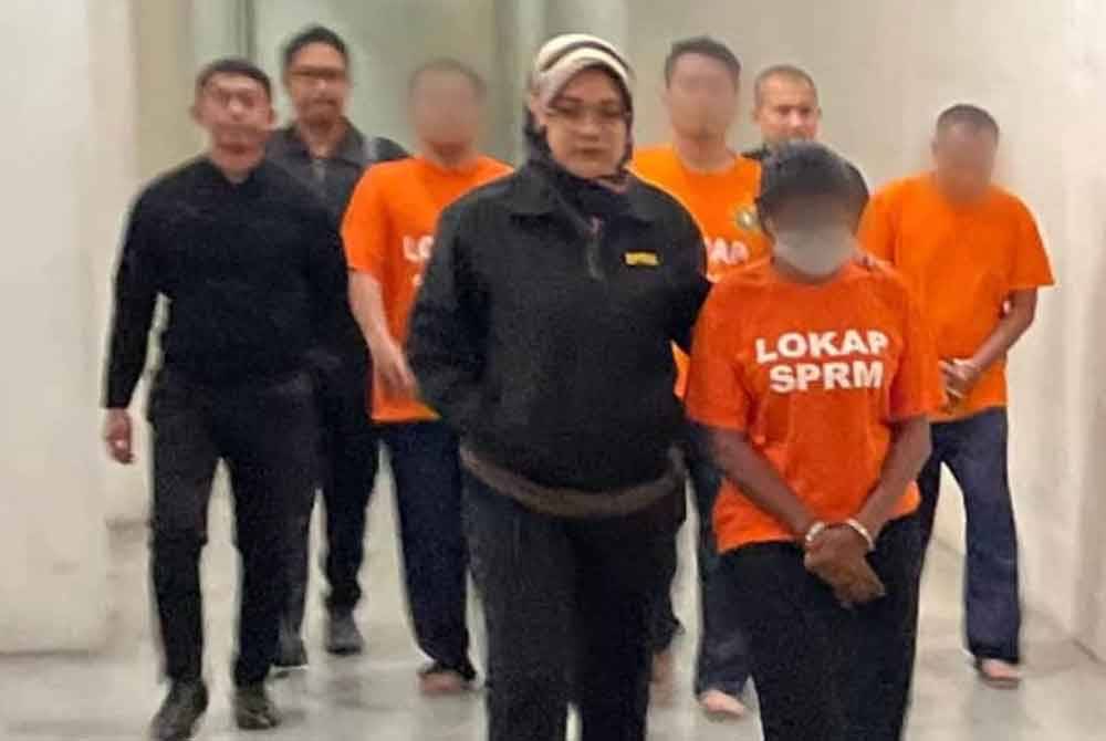 Suspek yang merupakan bekas ketua jabatan syarikat insurans (depan, kanan) dibawa ke Mahkamah Majistret Kuala Lumpur kerana dipercayai meminta dan menerima wang rasuah berjumlah RM500,000.