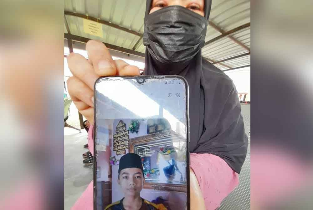 Suhana menunjukkan foto Muhammad Airell yang menjadi korban bersama rakannya ketika mandi di parit Kampung Perpat, Tanjung Sedili, Kota Tinggi, pada Rabu.