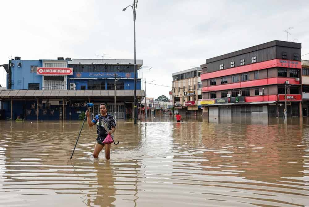 Seorang penduduk setempat meredah banjir ketika tinjauan di Bandar Kota Tinggi pada Rabu. Foto Bernama