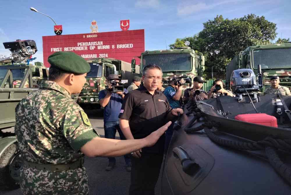 Adly (kanan) melihat aset yang digunakan ATM untuk membantu mangsa banjir.