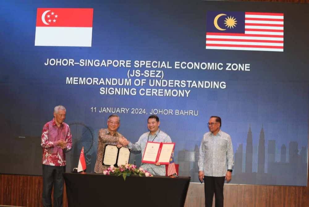 Anwar (kanan) bersama Hsien Loong (kiri) menyaksikan majlis MoU antara Rafizi (dua, kanan) dengan Kim Yong di Johor Bahru pada Khamis.