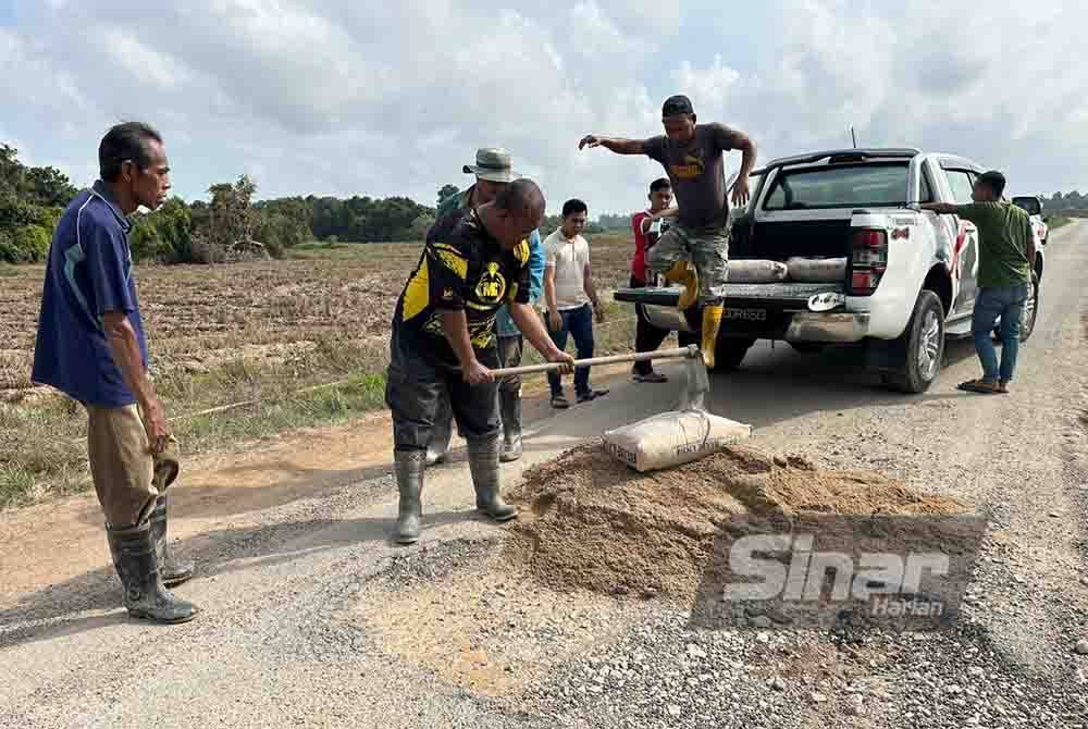 Kerja-kerja menampal lubang jalan dilakukan penduduk kampung.