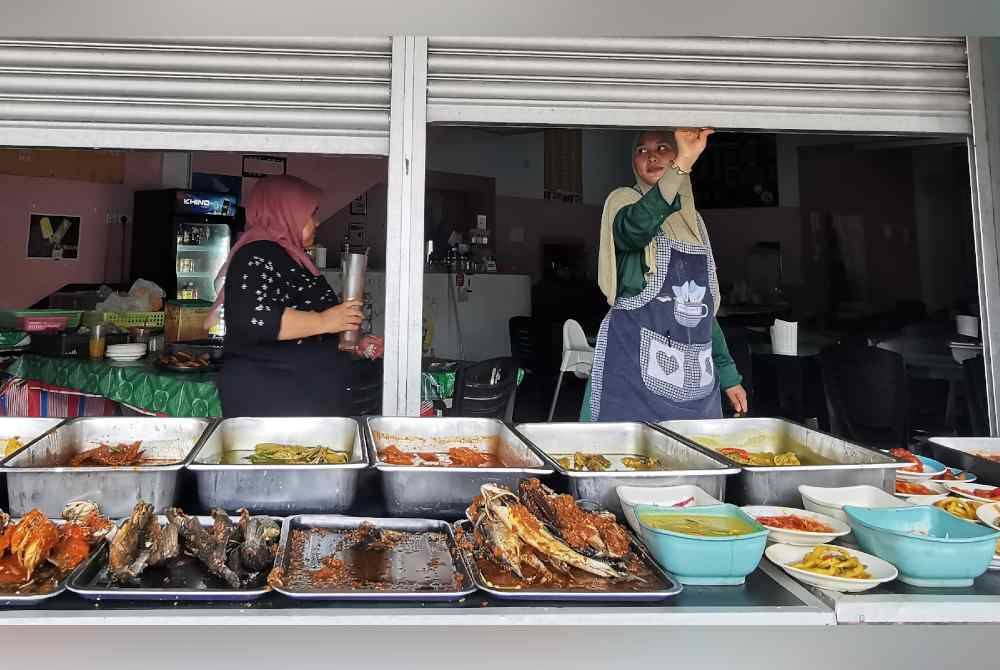 Seorang pekerja sebuah kedai makan menutup pintu kedai bermula jam 12.30 tengah hari pada Jumaat.