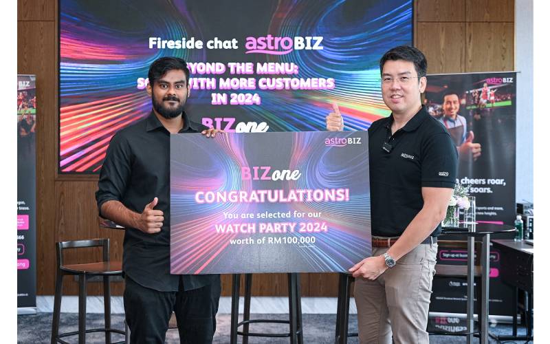 Kam Leong (kanan) menyerahkan hadian cabutan Astro BIZone Watch Party yang bernilai RM100,000 kepada seorang wakil restoran terpilih,