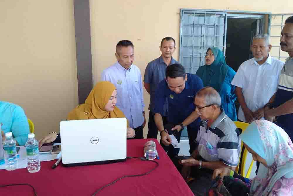 Mohd Azlan (berdiri tiga dari kiri) ketika lawatan ke Kaunter Bergerak Daftar PADU di Dewan Orang Ramai Kampung Batu 1, Jalan Tanjung Tualang, di sini pada Sabtu.