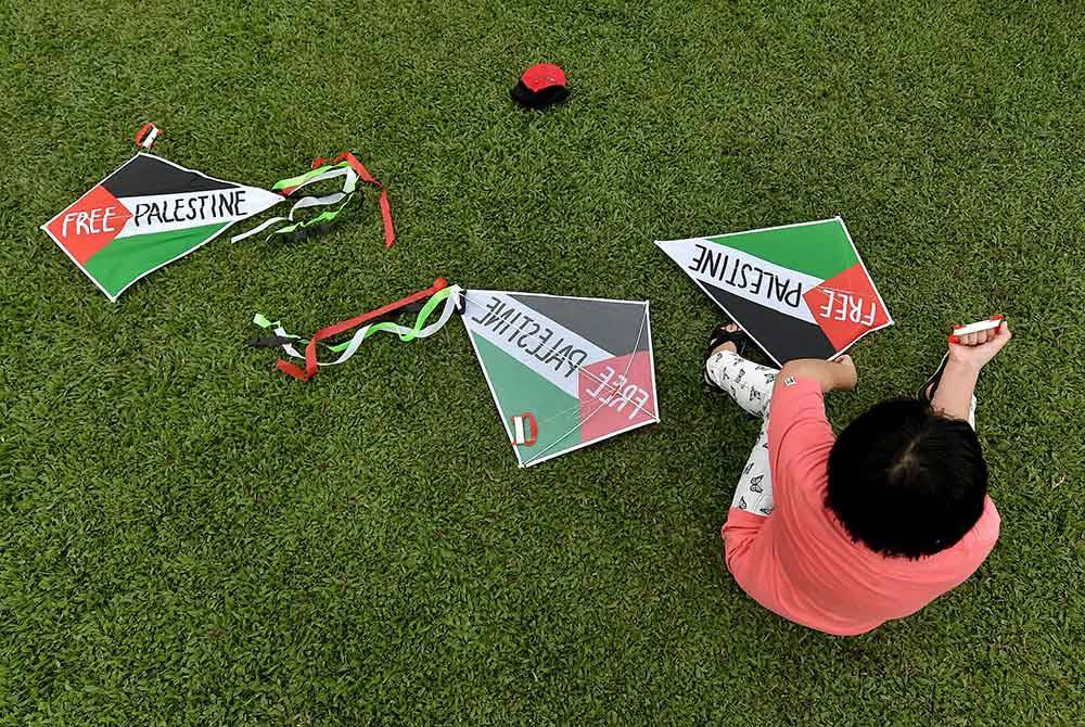 Peserta cilik bersama layang-layangnya ketika menyertai aktiviti 'Fly Kite for Gaza' di MST Golf Driving Range @ Bukit Jelutong Golf Centre pada Ahad. Foto Bernama