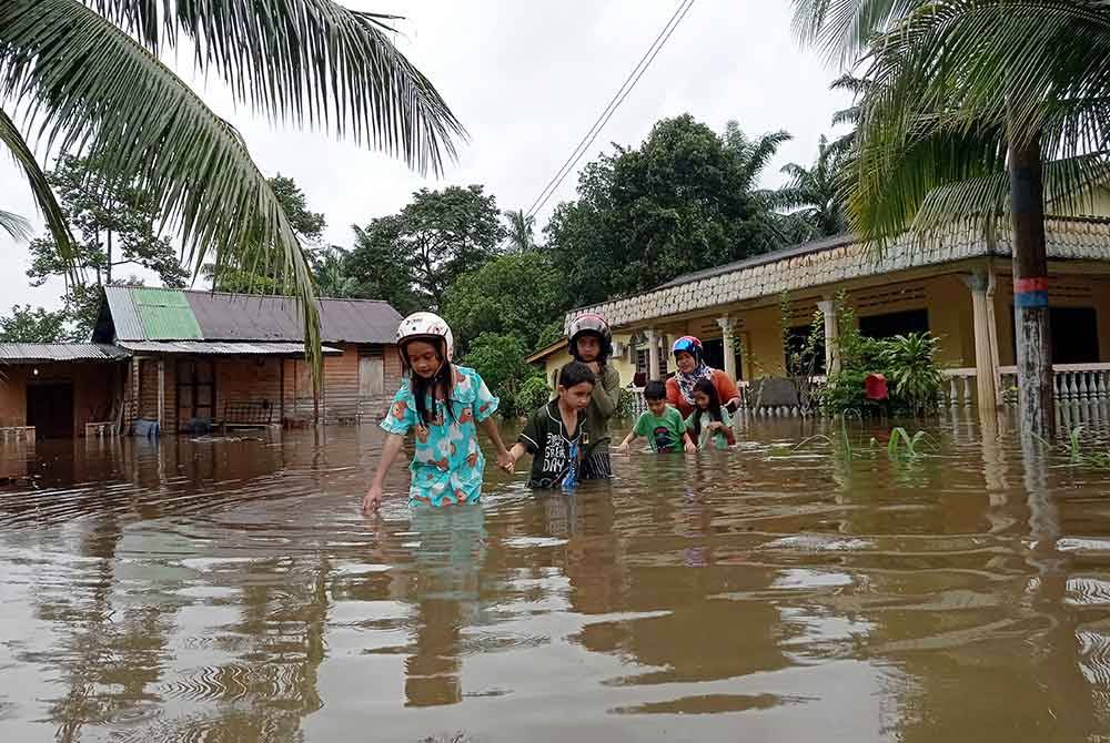 Penduduk Kampung Tenglu Besar, Mersing meredah air berikutan kediaman mereka dilanda banjir. Foto Bernama