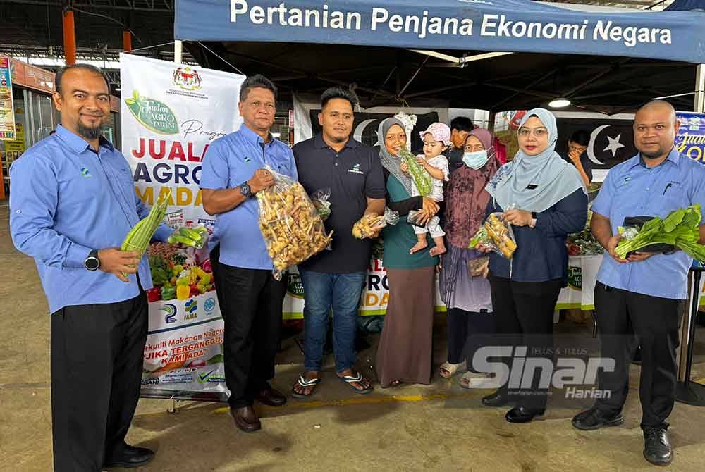 Abd Rahman (dari dari kiri) dan Wan Faizatul Aniza (dua dari kanan) menunjukkan sayur-sayuran yang boleh didapati di Program Jualan Agro Madani di Tunjong, Kota Bharu.