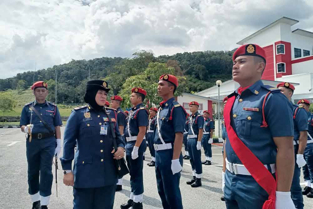 Sayani (kiri) melakukan pemeriksaan perbarisan kehormat sempena Amanat Pengarah Tahun 2024 di Ibu Pejabat JBPM Perak pada Isnin.