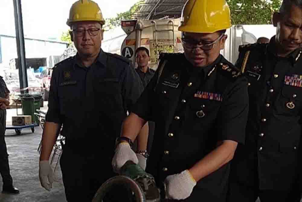 Kamalludin (tengah) melakukan gimik pelupusan barangan rampasan sempena Program Pelupusan Ekshibit Perdana di Stor Penyimpanan Ekshibit KPDN Perak, Kawasan Perusahaan IGB di Ipoh pada Selasa.