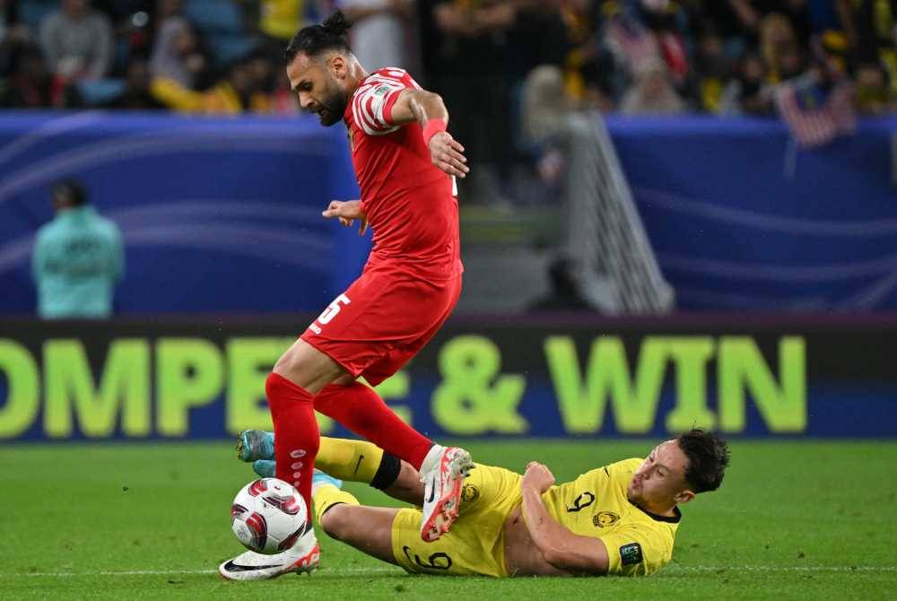 Yazan (kiri) diasak pemain Harimau Malaya, Darren Lok dalam aksi Kumpulan E Piala Asia Qatar 2023 di Stadium Al-Janoub, Al-Wakrah. Foto AFP