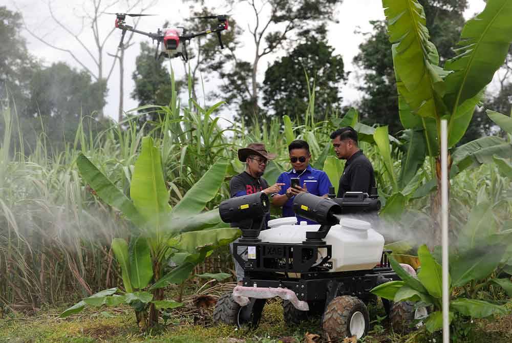 Pemilik syarikat Temin Legacy Sdn Bhd Mejar (B) Mohd Farid Daud (tengah) melihat dron udara (UAV) dan darat (UGV) yang digunakan bagi meracun dan membaja di ladang integrasi moden di Labu Hilir dekat sini. Foto Bernama