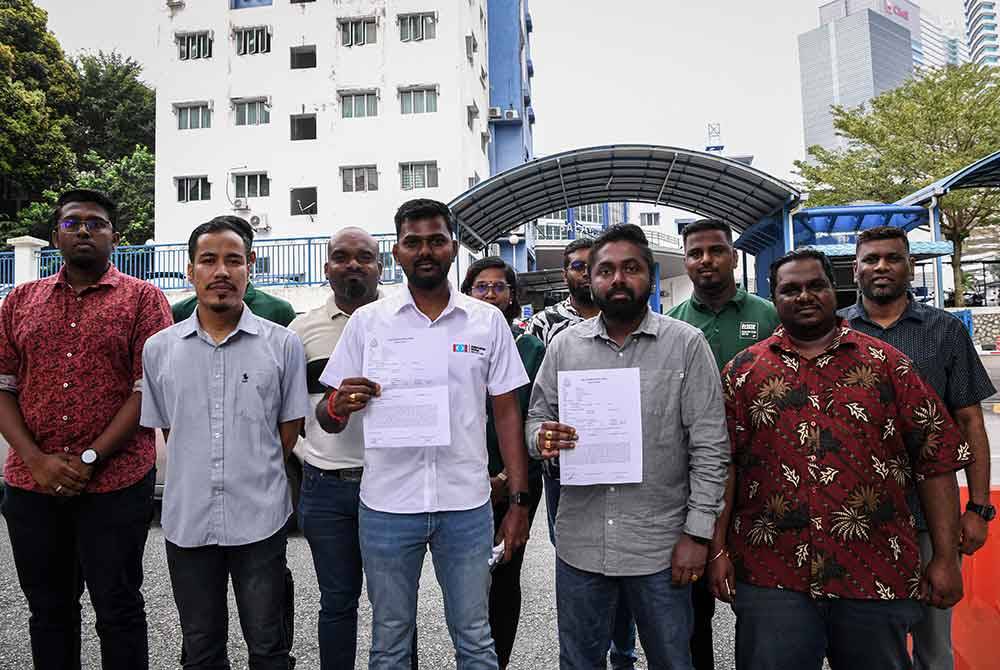 Sathasivam (depan tiga, kiri) menunjukkan laporan polis berhubung kenyataan Tun M ketika ditemui pemberita di hadapan Balai Polis Travers hari ini. Foto Bernama