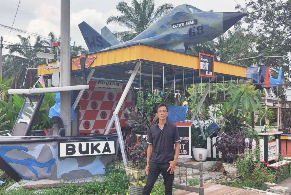 Rahman di hadapan dua replika pesawat dan bot di warungnya di Kampung Bukit Hijau, Kuala Selangor.