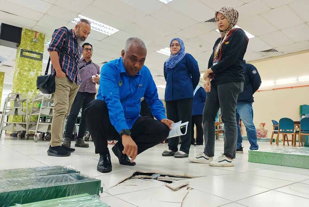 Khairudin melihat keretakan lantai yang berlaku ketika lawatan kerjanya ke Perpustakaan Awam Negeri Perak.