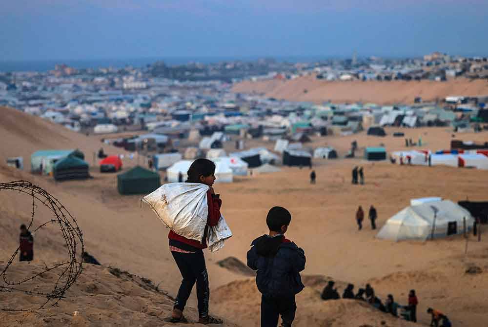 Kanak-kanak Palestin berjalan di atas bukit menghadap kem sementara mereka di Rafah, di selatan Semenanjung Gaza, sempadan Mesir pada Jumaat, di tengah-tengah pertempuran berterusan antara Israel dan pejuang Hamas. Foto AFP