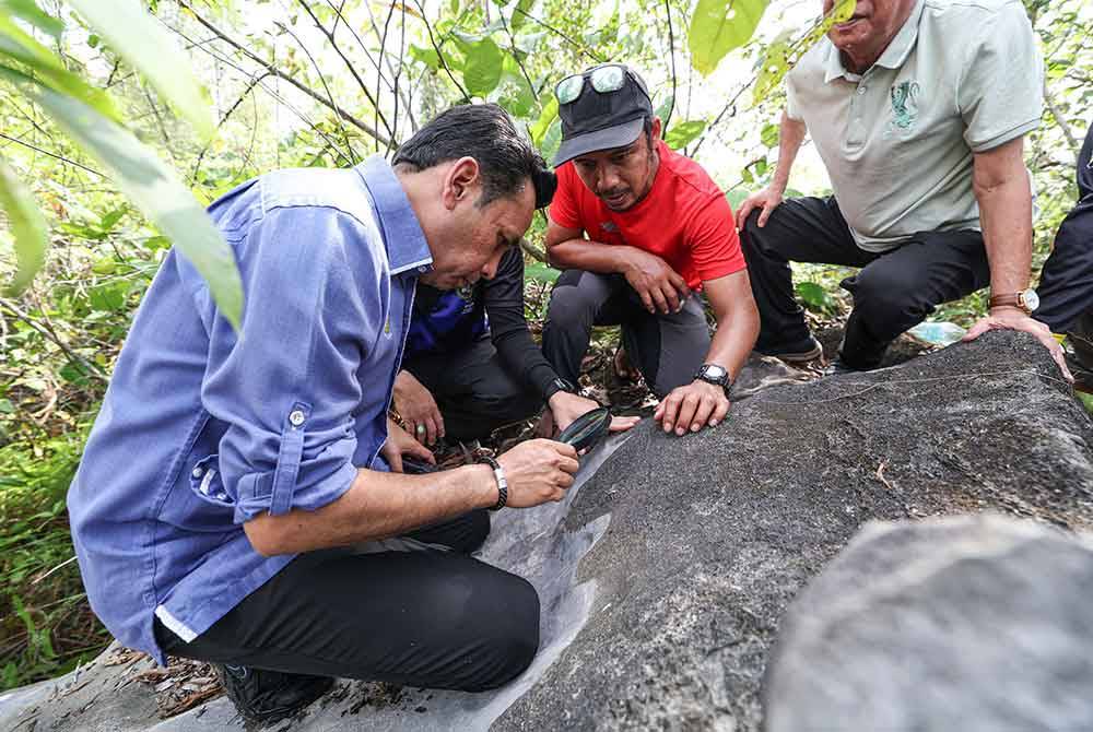 Mohd Azlan (kiri) meneliti fosil yang melekat pada batu-batuan ketika mengadakan lawatan ke sebuah kawasan berdekatan Kampung Changkat Tualang semalam. Foto Bernama