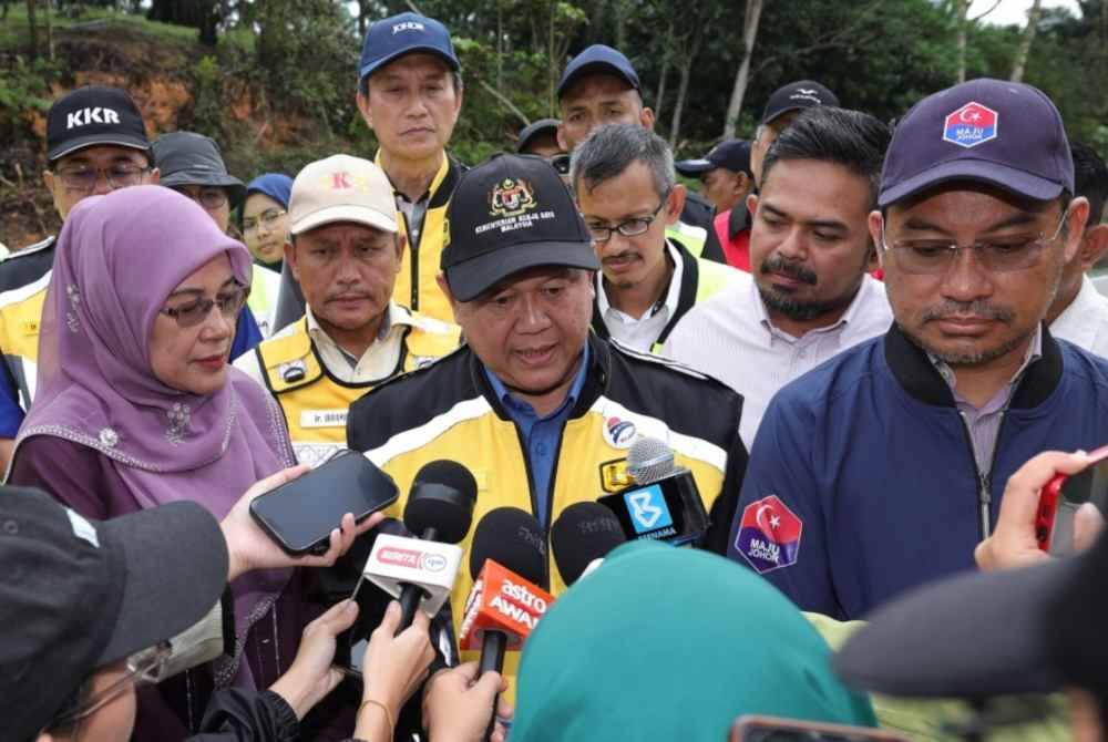 Menteri Kerja Raya, Datuk Seri Alexander Nanta Linggi (tengah) bercakap pada sidang media selepas melihat cerun bukit yang terjejas di laluan Johor Bahru - Endau pada lawatan kerja, pada Sbtu. Foto Bernama