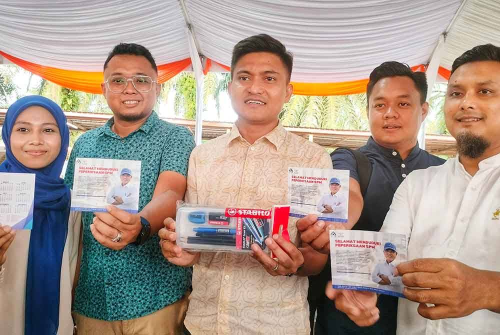 Kamil (tengah) menunjukkan kit alat tulis yang disediakan untuk calon SPM di Pahang.