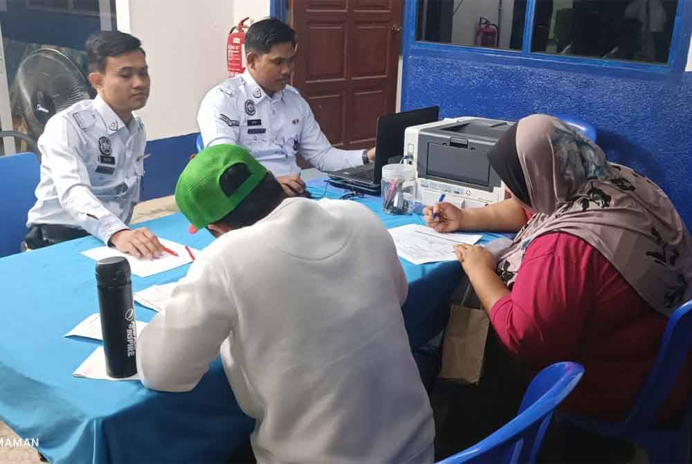 Orang ramai menyemak saman sempen Majlis Ngautim dengan OCPD yang diadakan di pekarangan Balai Polis Air Jernih, Kemaman.