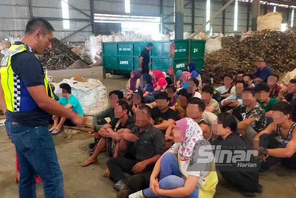 Hazril (kiri) bertanyakan sesuatu kepada warga asing yang ditahan di sebuah kilang barang lusuh di Telok Gong, Klang, Selangor pada Isnin.