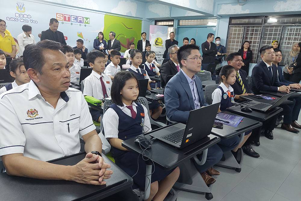 Kah Woh (depan, tiga dari kiri) menyaksikan sesi PdP hibrid antara SJKC Mun Yee dengan Sekolah Haixin, Qingdao, China sempena DIMIX@Karnival Digital pada Selasa.